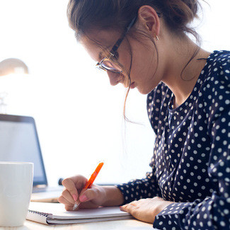 Young woman writing on notepad